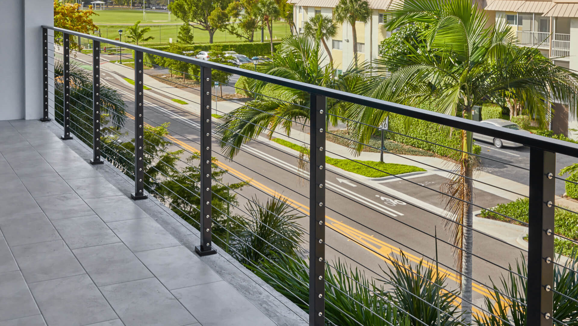 The Ultimate Guide to DIY Cable Railing for Decks DIY cable railing on a deck overlooking a coastal street with palm trees in the background