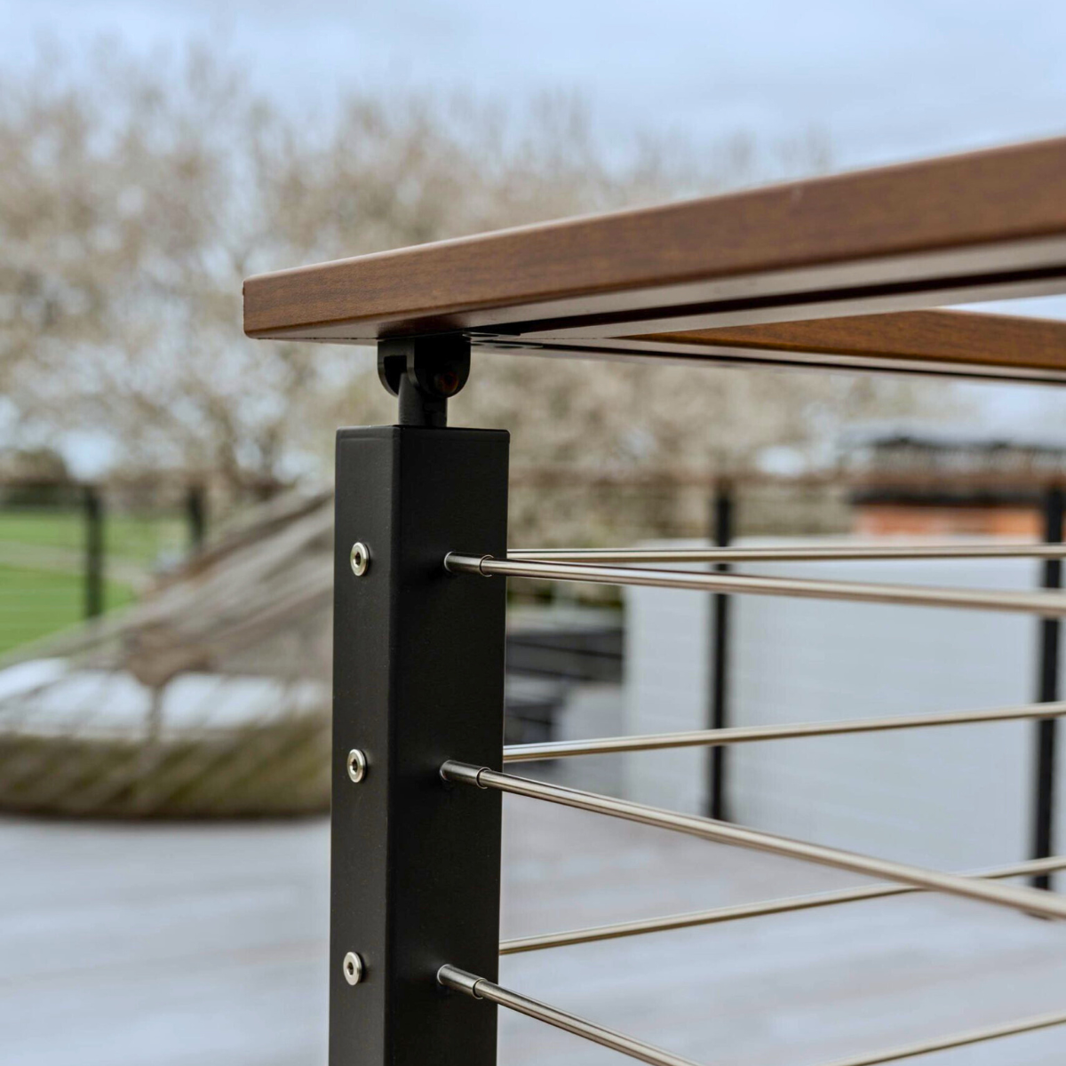 Closeup shot of a 90 degree turn using one post for the rod railing, also showing the aluminum handrail made to look like wood.