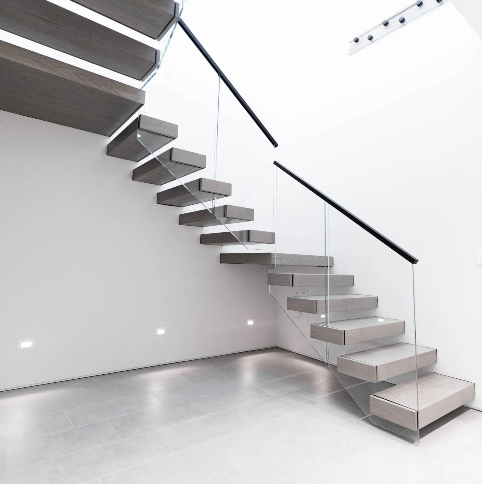 A U-Shape FLIGHT Cantilever with Vedera railing and Black handrail creates a sharp contrast with the bright white walls and light tile flooring.